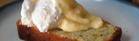 A slice of pepper-ginger pound cake sits on a small plate, topped with a scoop of vanilla ice cream and a light yellow cascade of pawpaw puree. Two pawpaw seeds sit on the plate as garnish.